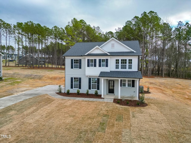 traditional home featuring central air condition unit, roof with shingles, and driveway