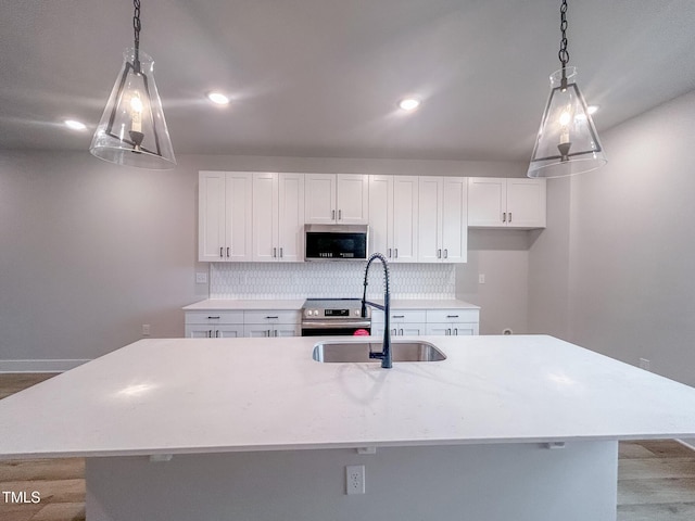 207 Pond View Ct Unit 3, Fuquay Varina, NC 27526 - kitchen featuring appliances with stainless steel finishes, a sink, decorative backsplash, white cabinetry, and an island with sink