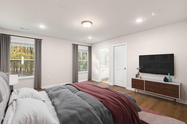 bedroom featuring connected bathroom and dark wood-type flooring