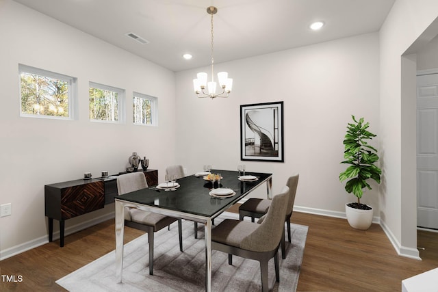 dining area with dark wood-type flooring and a chandelier