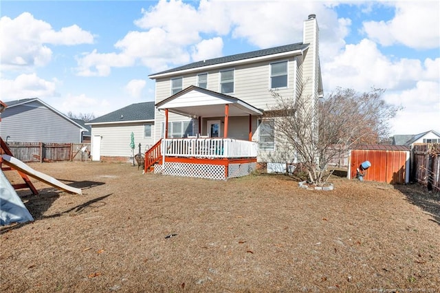 rear view of property featuring a deck and a storage unit