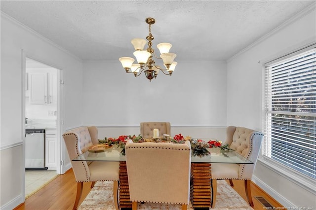 dining area featuring crown molding, an inviting chandelier, a textured ceiling, and light wood-type flooring