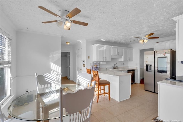 kitchen with kitchen peninsula, sink, a textured ceiling, a kitchen bar, and white cabinetry