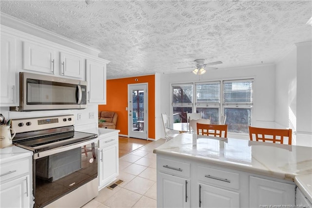 kitchen with ceiling fan, light tile patterned floors, a textured ceiling, appliances with stainless steel finishes, and white cabinetry