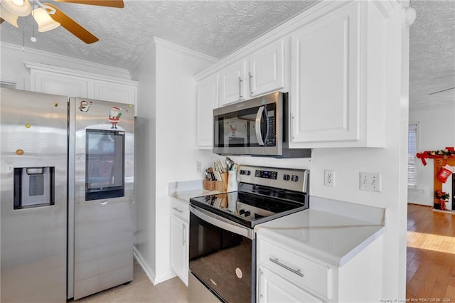 kitchen featuring appliances with stainless steel finishes, a textured ceiling, light hardwood / wood-style flooring, and white cabinetry