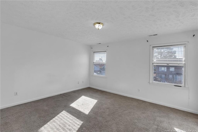 unfurnished room featuring plenty of natural light, dark carpet, and a textured ceiling