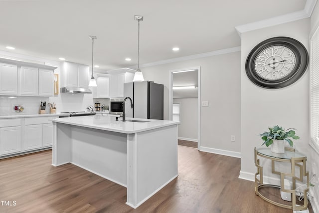 kitchen with white cabinets, stainless steel fridge, an island with sink, and pendant lighting