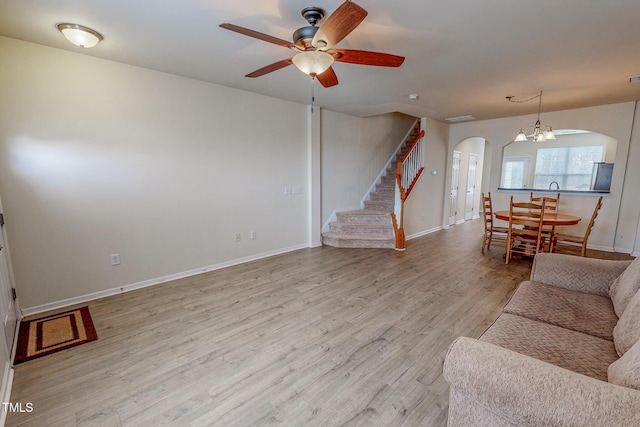 living room featuring ceiling fan with notable chandelier and light wood-type flooring