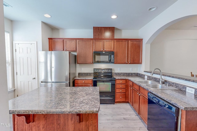 kitchen featuring a wealth of natural light, sink, light hardwood / wood-style flooring, a breakfast bar, and black appliances