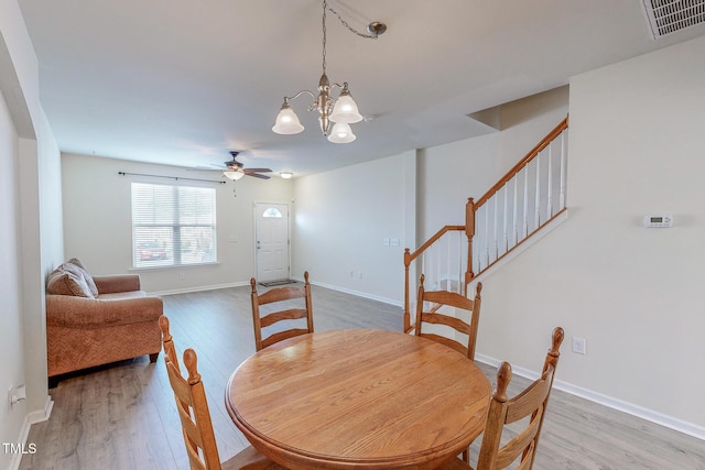 dining area with hardwood / wood-style floors and ceiling fan with notable chandelier