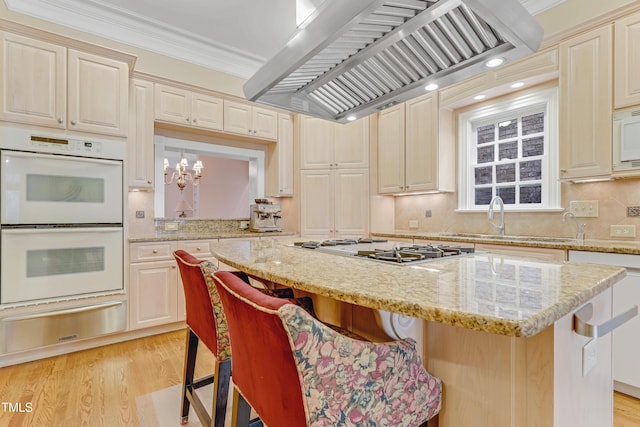 kitchen with island exhaust hood, a kitchen bar, light wood-type flooring, white appliances, and pendant lighting