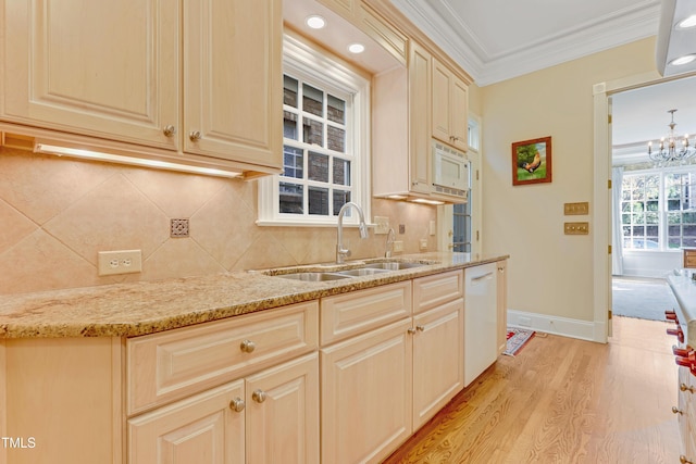 kitchen with white appliances, sink, light stone countertops, ornamental molding, and light hardwood / wood-style floors