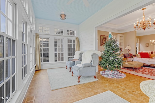 sunroom / solarium featuring ceiling fan with notable chandelier