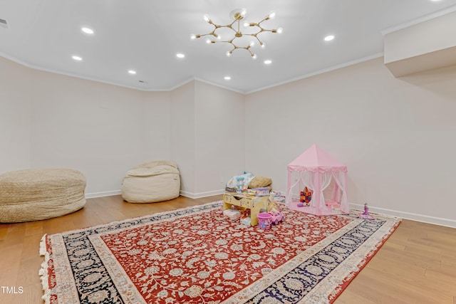 game room featuring a chandelier, hardwood / wood-style flooring, and crown molding