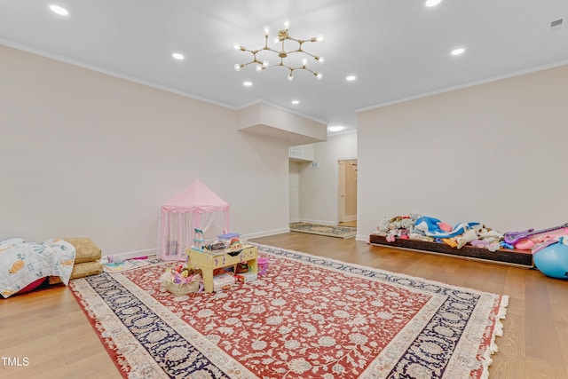 playroom with light hardwood / wood-style floors, an inviting chandelier, and ornamental molding