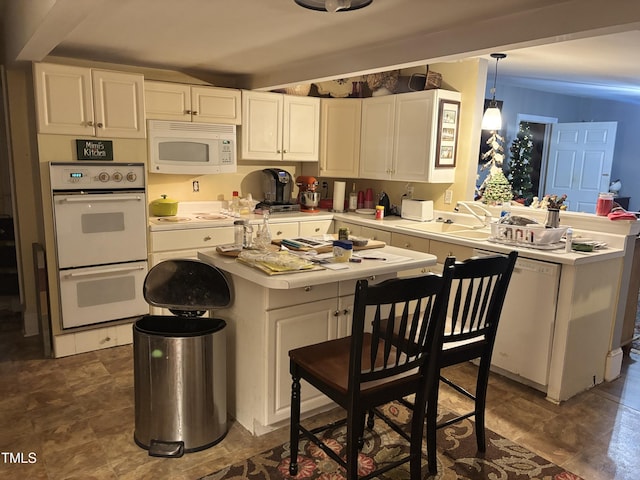 kitchen with sink, a kitchen island, pendant lighting, white appliances, and white cabinets