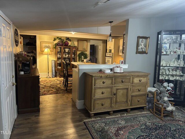 kitchen featuring lofted ceiling, hanging light fixtures, dark hardwood / wood-style floors, and kitchen peninsula