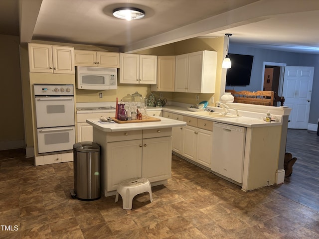 kitchen with sink, decorative light fixtures, kitchen peninsula, white appliances, and white cabinets