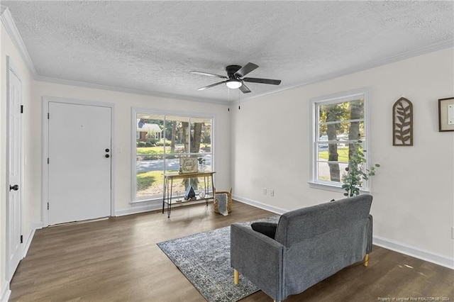 sitting room with a textured ceiling, ceiling fan, crown molding, and dark wood-type flooring