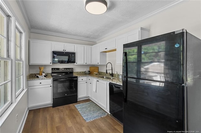 kitchen featuring light stone countertops, white cabinetry, crown molding, and black appliances