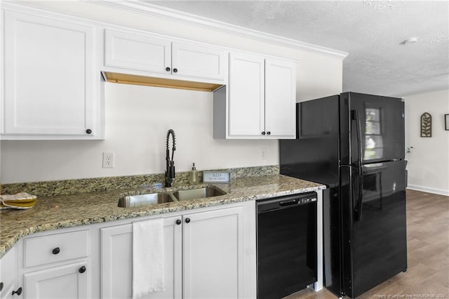 kitchen featuring black appliances, white cabinets, sink, hardwood / wood-style flooring, and light stone countertops