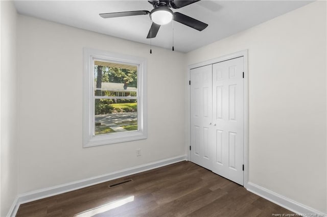 unfurnished bedroom with ceiling fan, a closet, and dark hardwood / wood-style floors