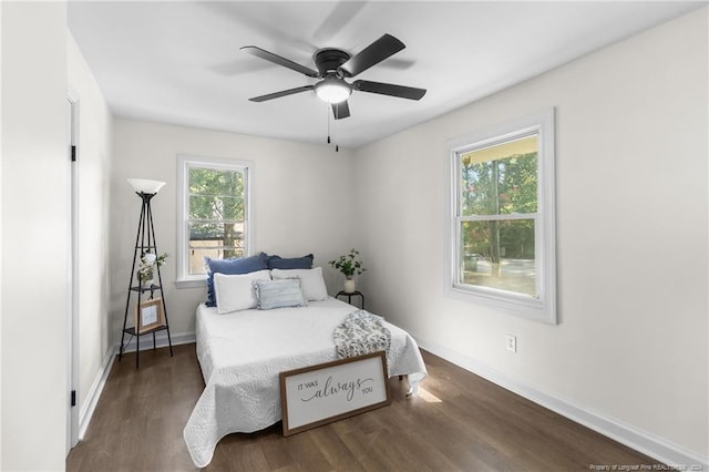 bedroom with multiple windows, ceiling fan, and dark hardwood / wood-style flooring