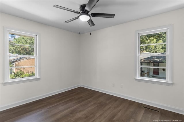 empty room with dark hardwood / wood-style flooring, a wealth of natural light, and ceiling fan