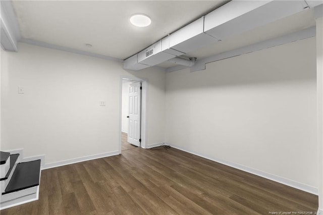 basement with dark hardwood / wood-style floors and ornamental molding