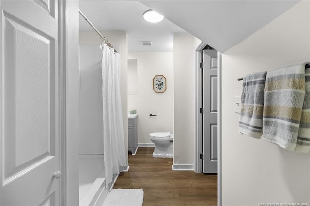 bathroom with curtained shower, vanity, wood-type flooring, and toilet