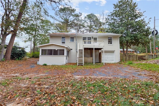 rear view of property featuring a sunroom, a garage, and a wooden deck