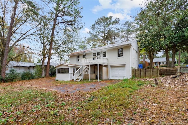 back of property featuring a sunroom, a garage, and a deck