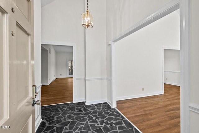 foyer with high vaulted ceiling, a chandelier, baseboards, and wood finished floors