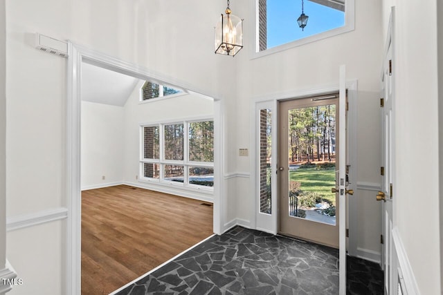 entryway featuring an inviting chandelier, baseboards, high vaulted ceiling, and dark wood-type flooring