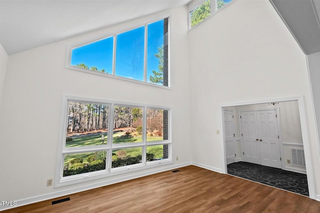 interior space with a towering ceiling, multiple windows, wood finished floors, and visible vents