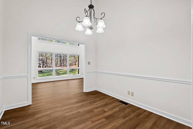 unfurnished dining area with baseboards, wood finished floors, visible vents, and a notable chandelier