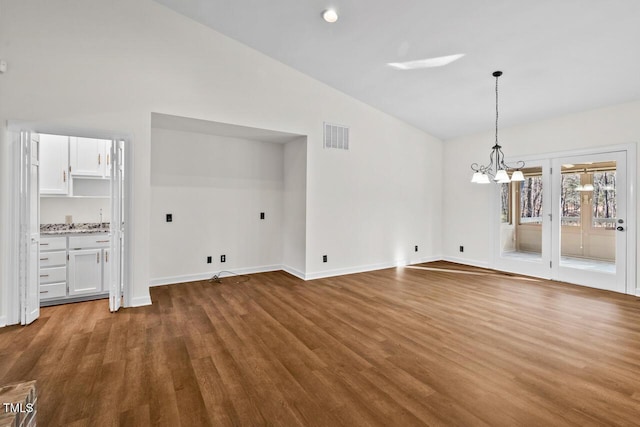 unfurnished dining area with dark wood finished floors, visible vents, vaulted ceiling, and an inviting chandelier