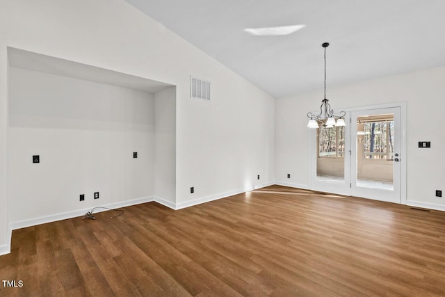 unfurnished dining area featuring a notable chandelier, wood finished floors, visible vents, baseboards, and vaulted ceiling