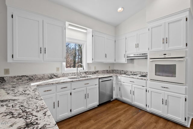 kitchen featuring white appliances, light stone countertops, under cabinet range hood, white cabinetry, and a sink