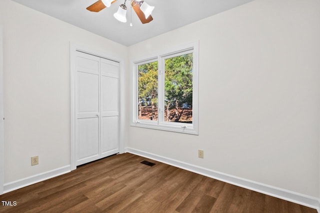 unfurnished bedroom featuring a closet, visible vents, dark wood-type flooring, ceiling fan, and baseboards