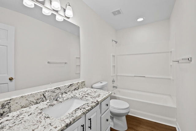 bathroom featuring toilet, wood finished floors, vanity, visible vents, and washtub / shower combination