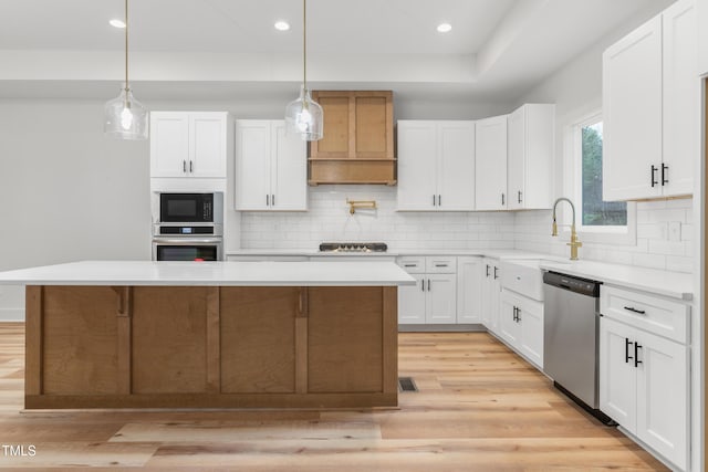 kitchen featuring white cabinetry, a center island, hanging light fixtures, and appliances with stainless steel finishes