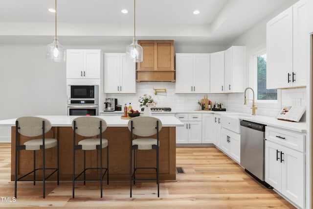 kitchen with white cabinets, decorative light fixtures, stainless steel appliances, and a kitchen island