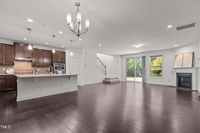 unfurnished living room featuring a chandelier, dark wood-type flooring, and sink