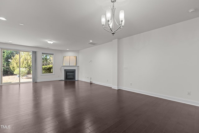 unfurnished living room featuring a notable chandelier and dark hardwood / wood-style flooring