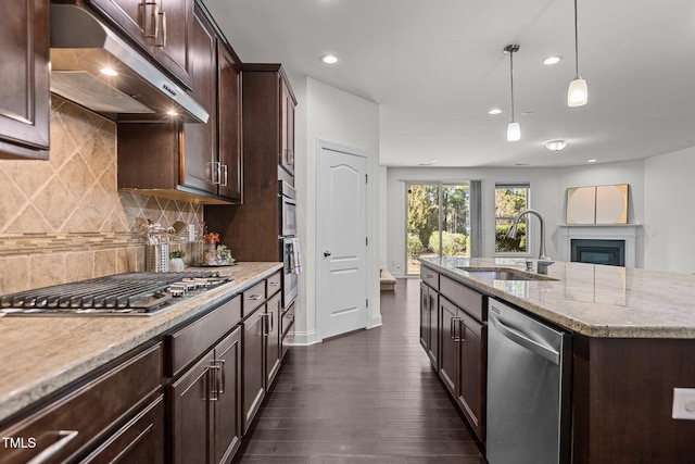 kitchen with light stone countertops, sink, dark wood-type flooring, hanging light fixtures, and appliances with stainless steel finishes