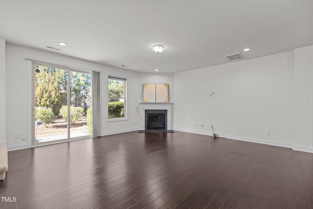 unfurnished living room featuring a healthy amount of sunlight and dark wood-type flooring