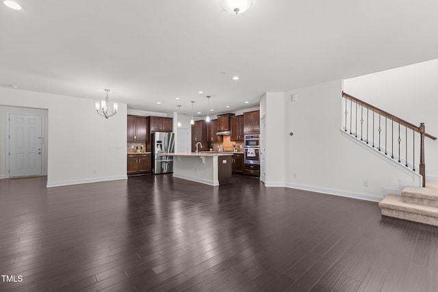 unfurnished living room featuring dark hardwood / wood-style flooring, an inviting chandelier, and sink