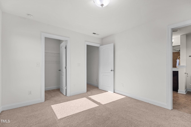 unfurnished bedroom featuring light carpet, a walk in closet, and a closet