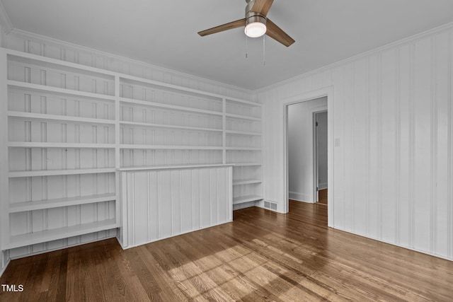 unfurnished living room featuring wood-type flooring, built in features, ceiling fan, and crown molding